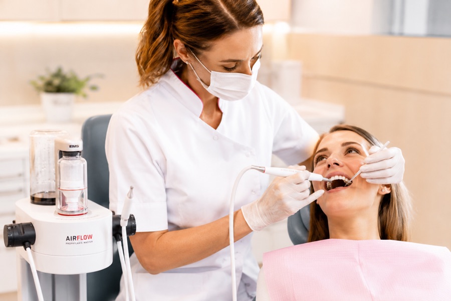 Dental hygienist performing Guided Biofilm Therapy on a patient in a treatment chair